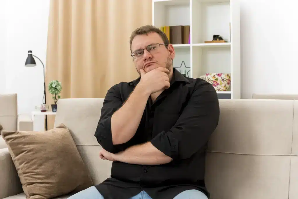 Un hombre sentado en su sofá pensando sobre cuándo operarse de obesidad